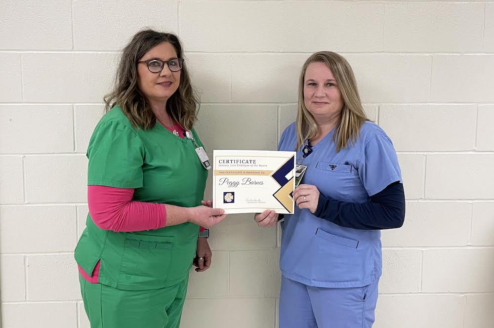 Two women in scrubs holding a sign