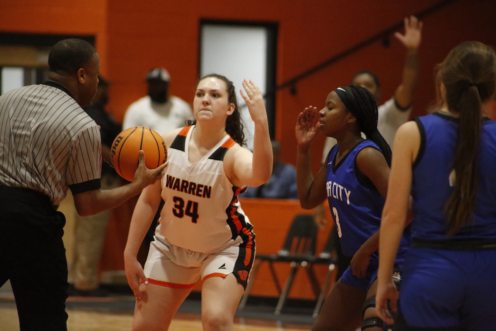 A girl is playing basketball in front of some people.