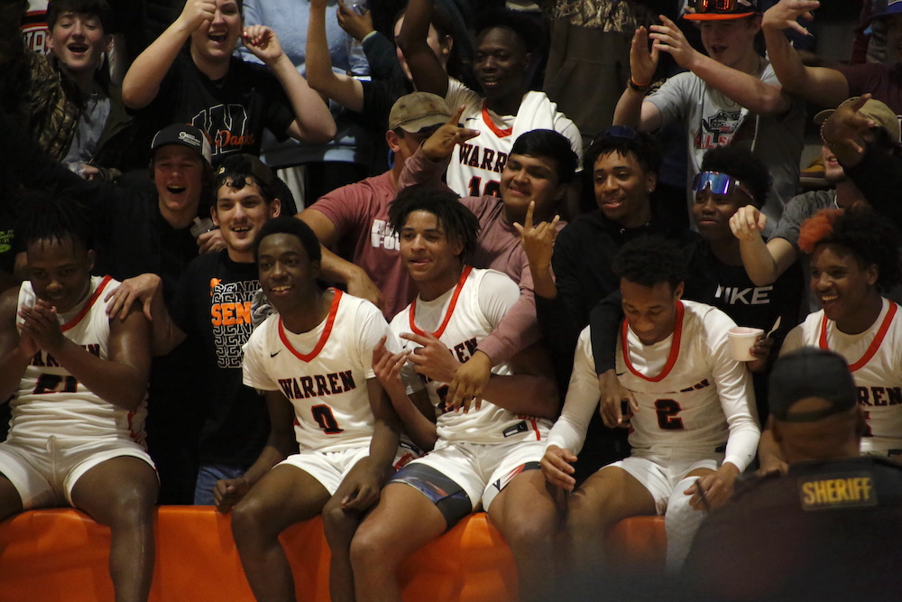 A group of men sitting on top of a basketball court.