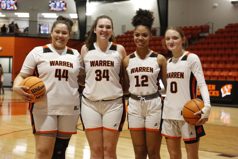 A group of girls standing next to each other holding basketballs.
