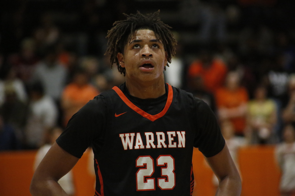 A young man in black and orange shirt playing basketball.