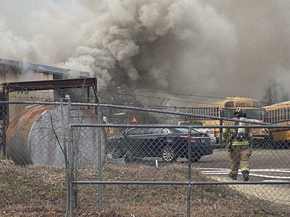 A fire truck is on the scene of a house fire.