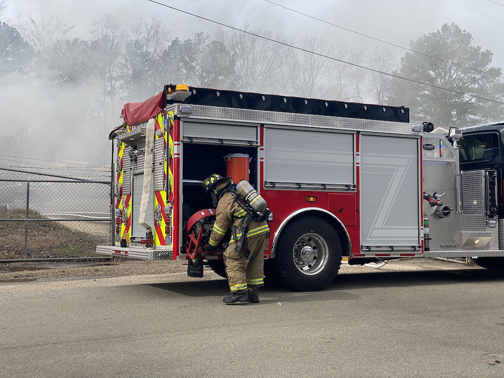 A fireman standing next to a fire truck.