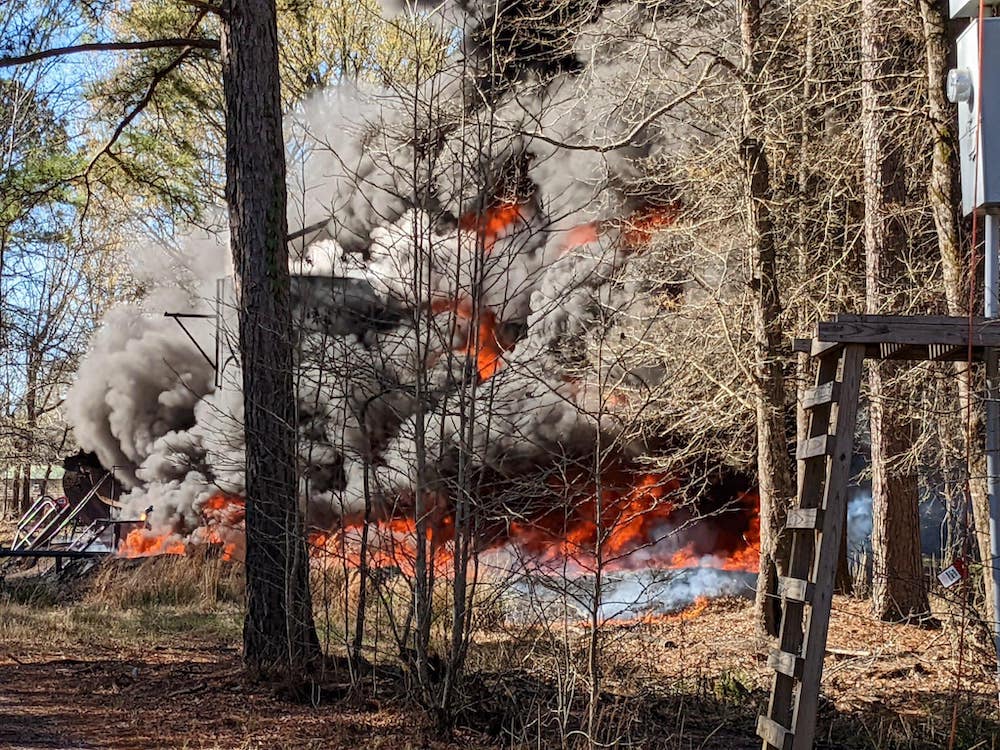 A forest fire with smoke billowing out of it.