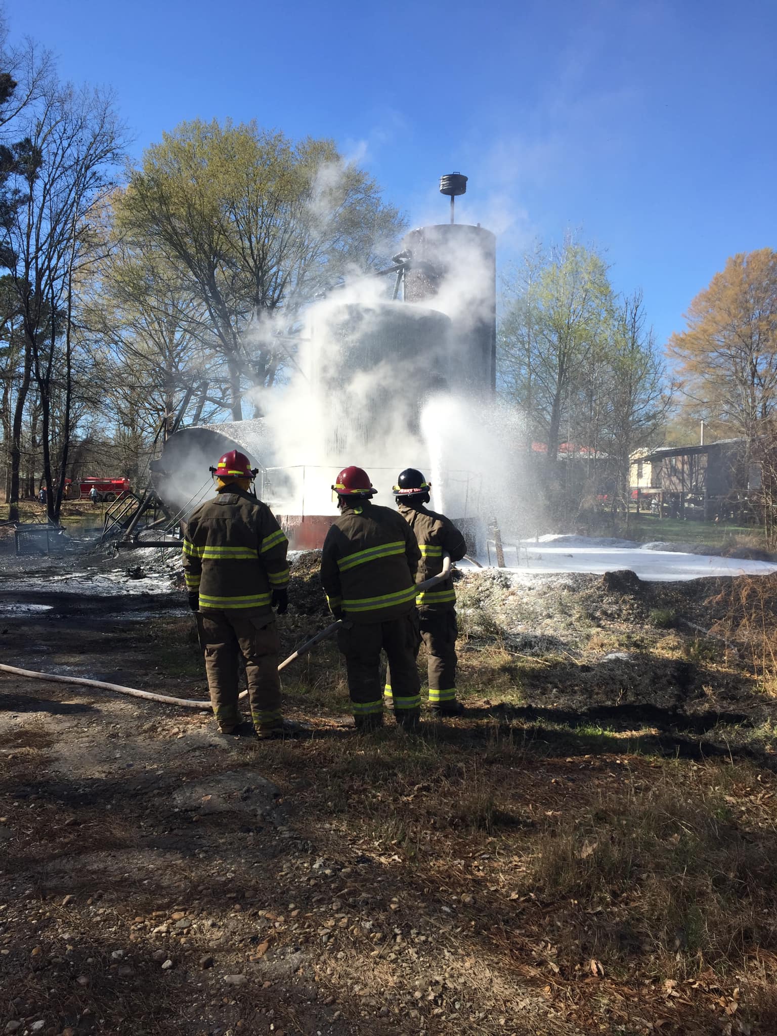 Three firemen standing in front of a fire hydrant.