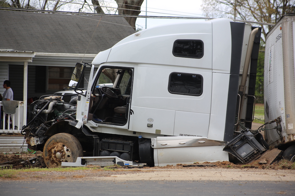 A white semi truck that has been smashed in to pieces.