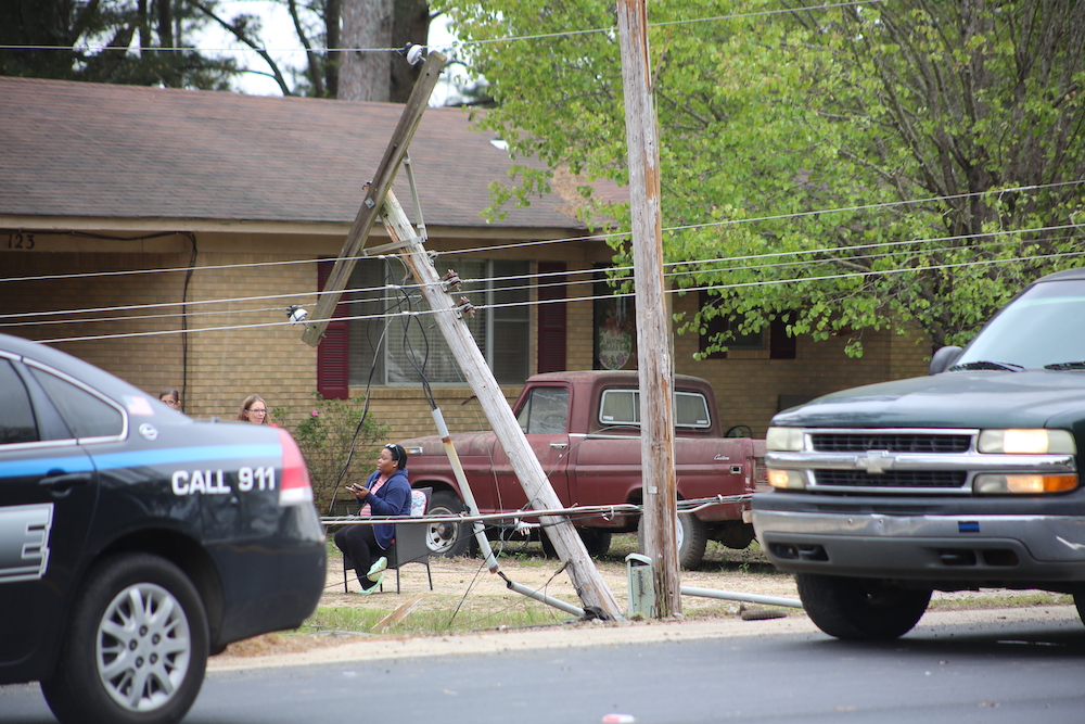 A man sitting on the side of a pole next to a truck.