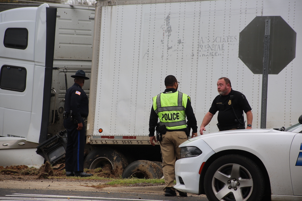 A police officer standing next to a white truck.