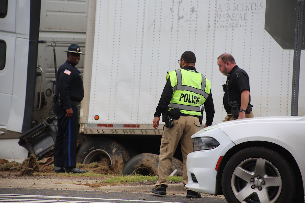 A police officer and two other men standing next to a truck.