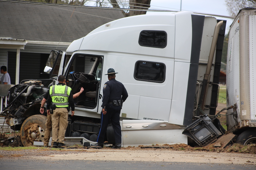 A police officer and two other people standing next to a truck.