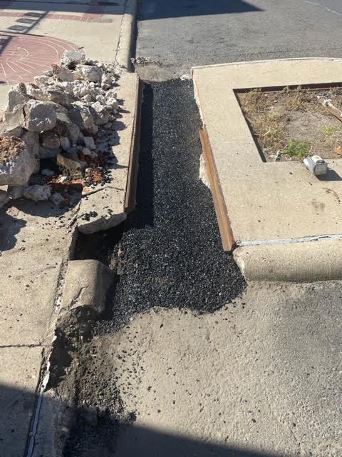 A broken curb with debris on the side of it.