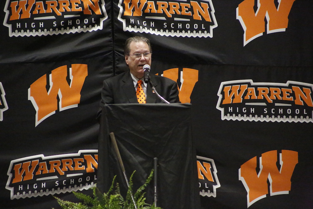 A man in black jacket standing at podium.