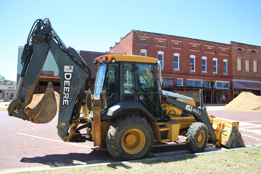 A yellow and black tractor parked in front of some buildings