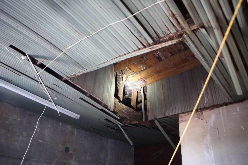 A light is shining in the ceiling of an unfinished room.