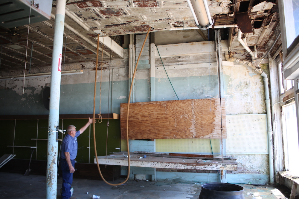 A man standing in front of an old wooden board.