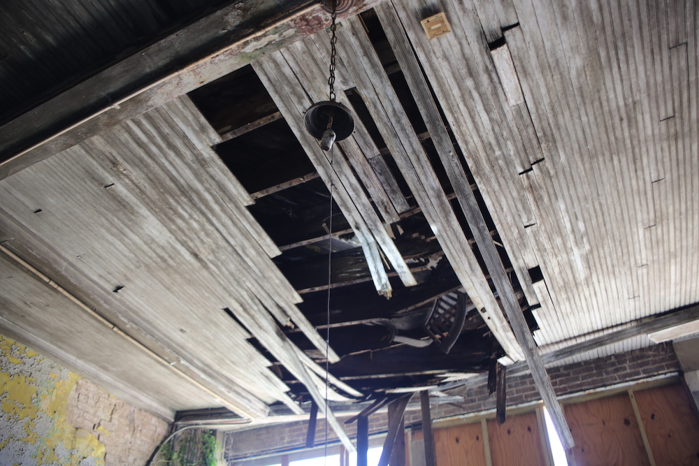 A ceiling with some wood planks and wires hanging from it