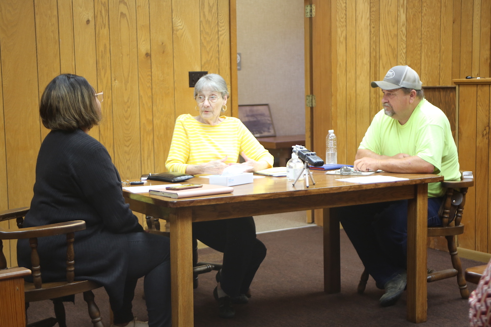 Three people sitting at a table in front of papers.