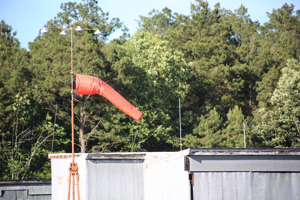 A red pipe is hanging over the top of a fence.