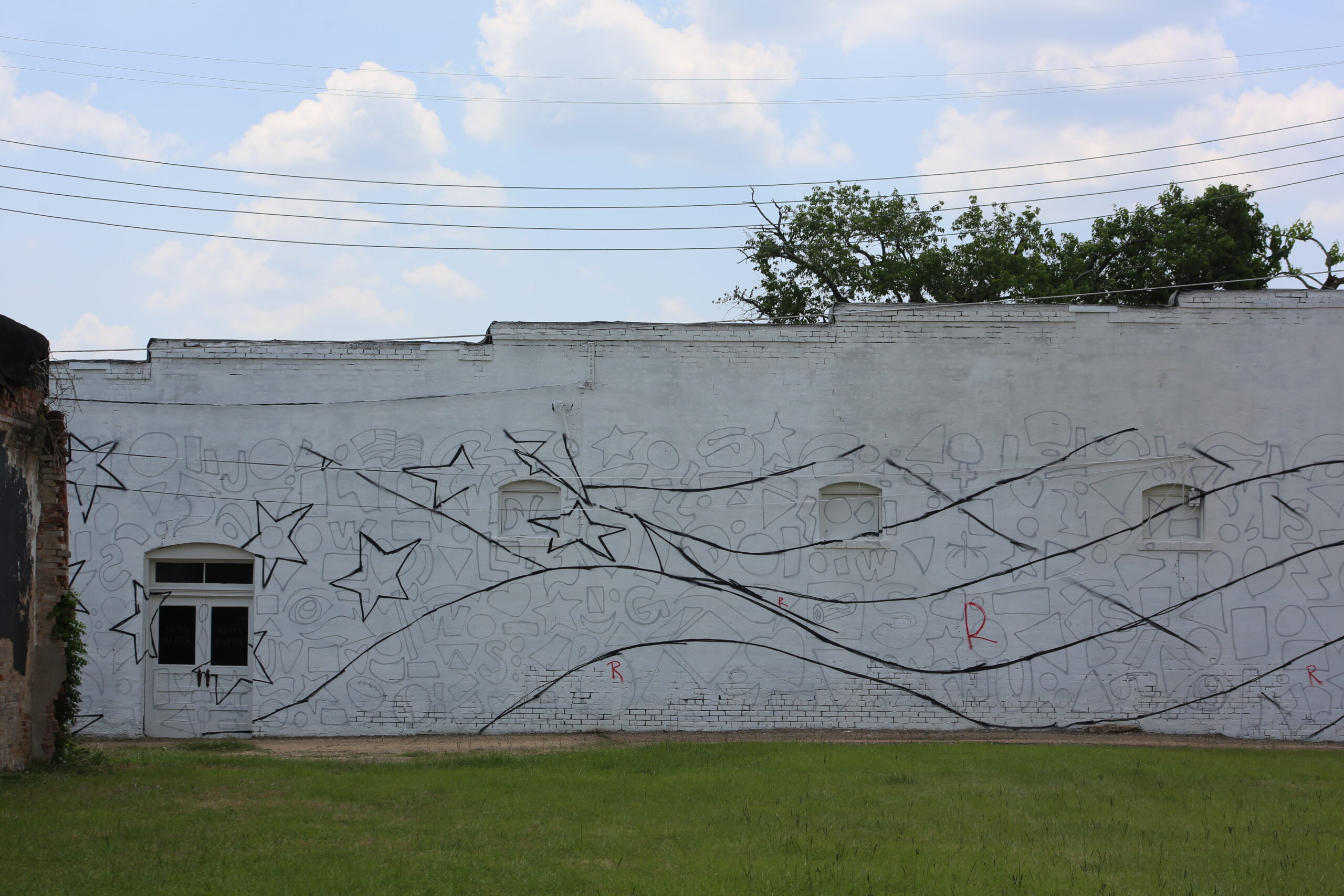 A white building with a tree and star mural on the side.