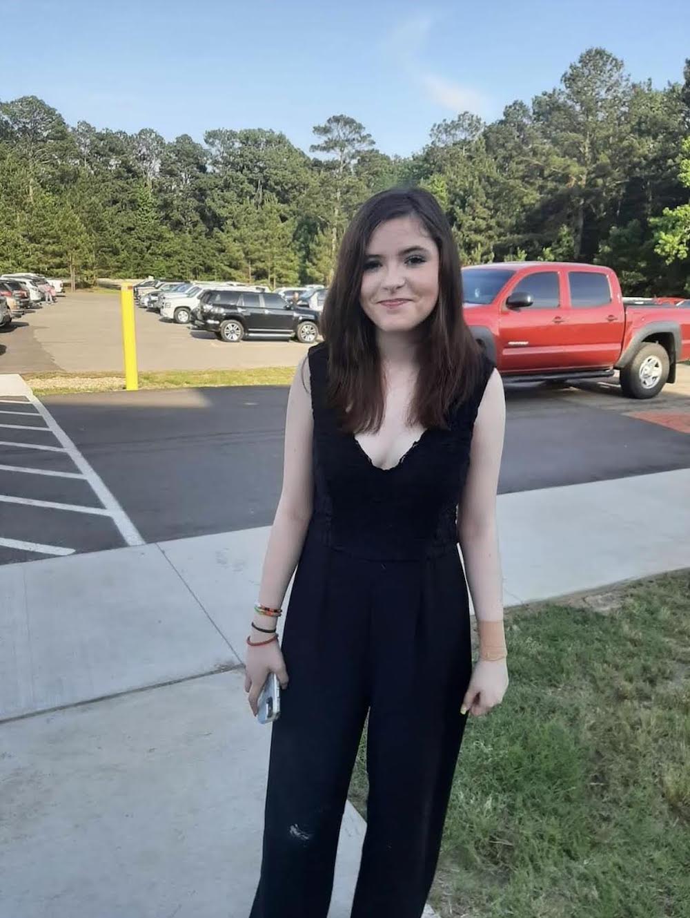 A woman in black dress standing on the sidewalk.