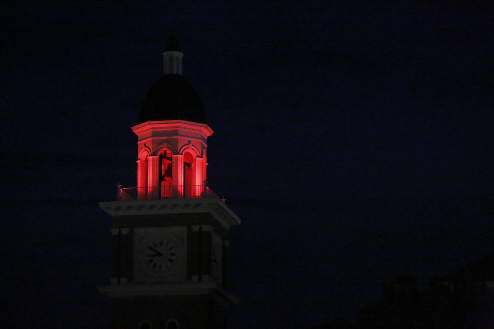 A clock tower with a red light on it's top.