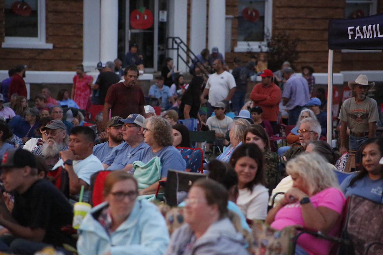 A crowd of people sitting in the sun.