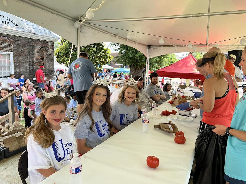 A group of people sitting at a table under a tent.