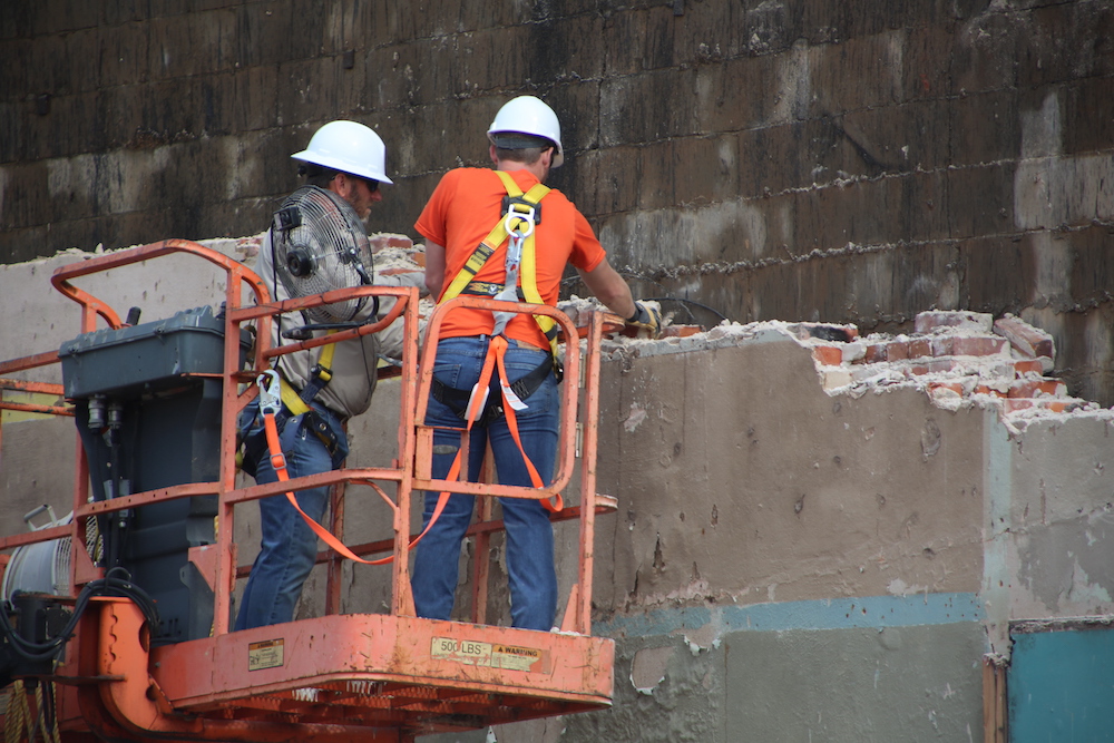 Two construction workers are working on a building.