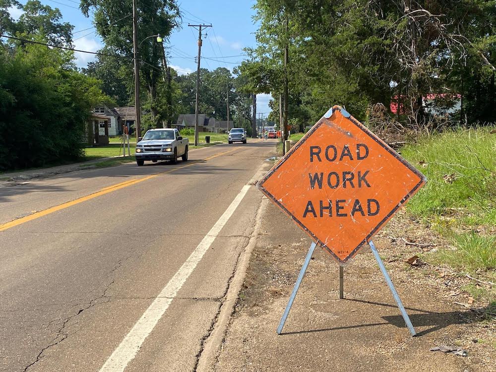 A road work ahead sign on the side of a street.