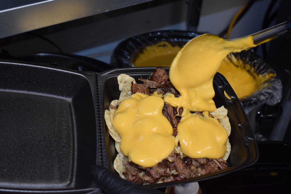 A close up of a burger with cheese sauce