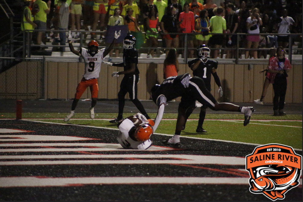 A football player falling to the ground after catching a pass.
