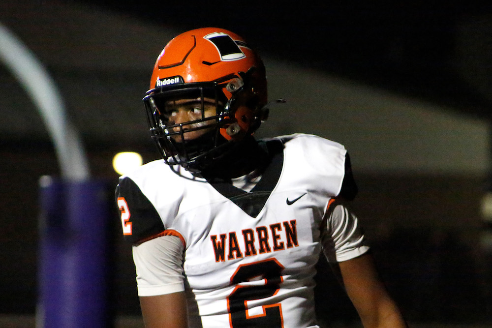 A football player in uniform is walking on the field.