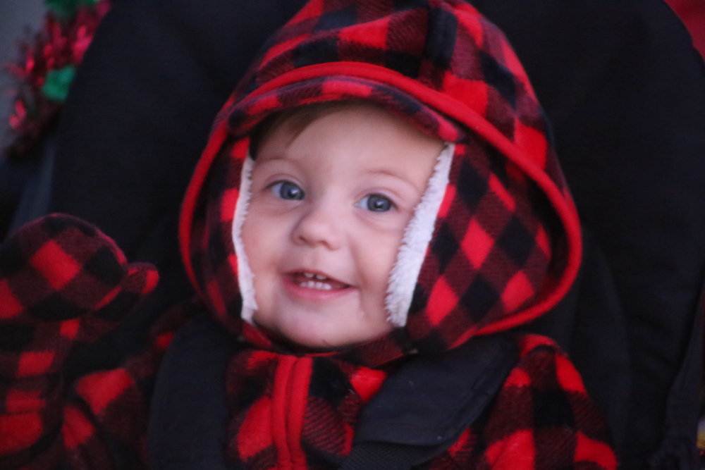 A baby in a red and black plaid coat.