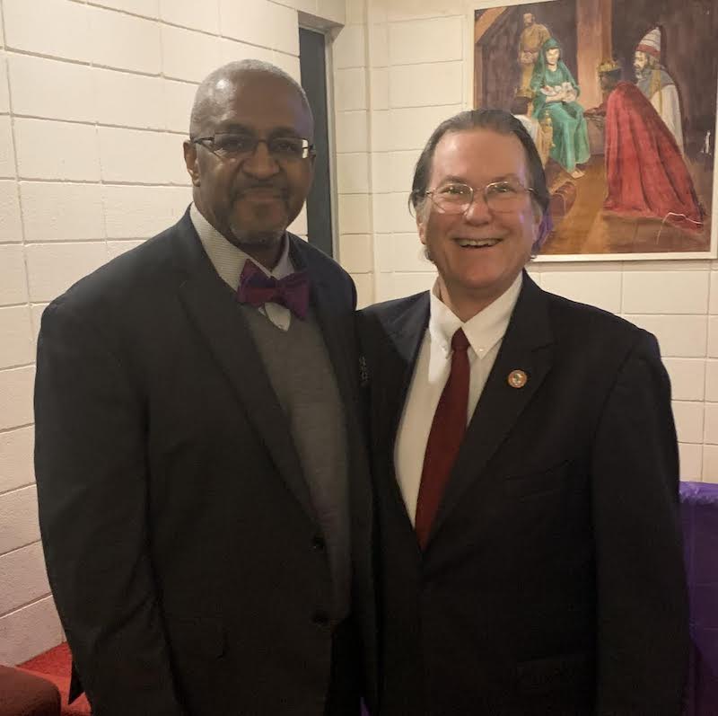 Two men in suits posing for a picture.