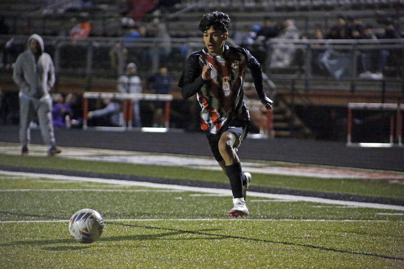 A man kicking around a soccer ball on the field.
