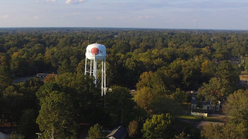 A water tower in the middle of a forest.
