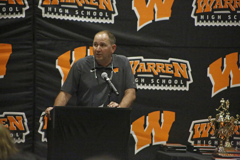 A man standing at a podium in front of a wall.
