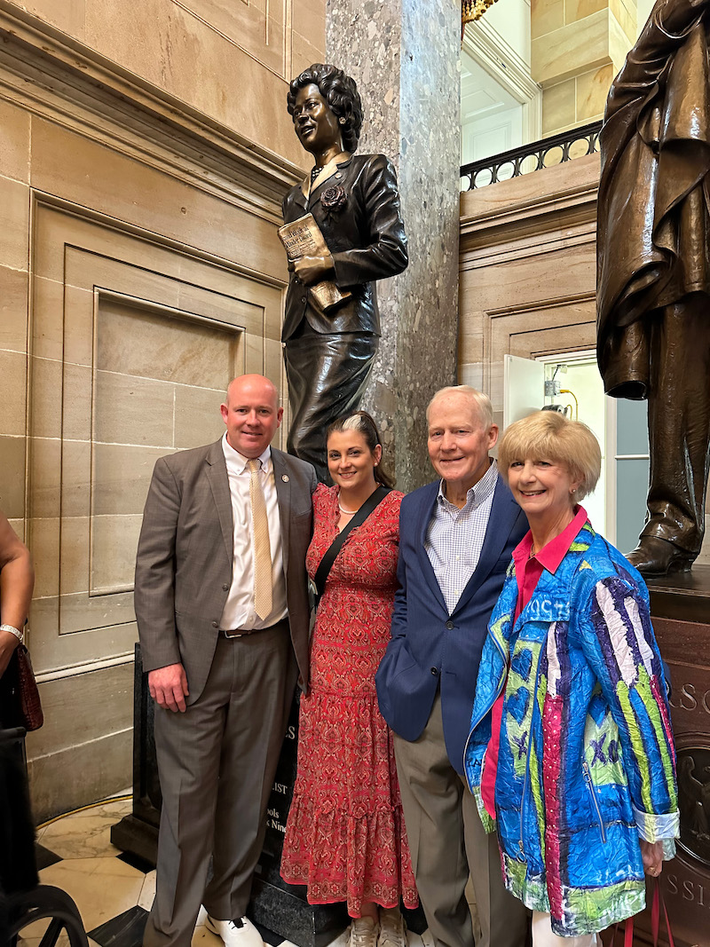 A group of people standing in front of a statue.