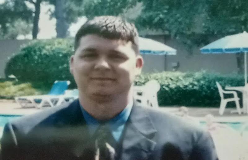 A man in a suit and tie smiling for the camera.