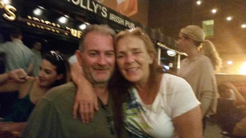 A man and woman are hugging in front of a pub.