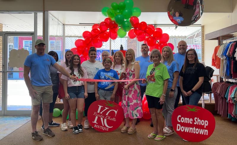 A group of people standing around each other holding a ribbon.