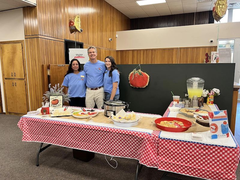 Three people standing in front of a table with food.