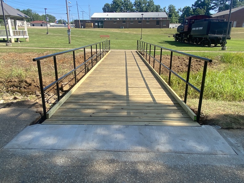 A wooden bridge with metal rails going over it.