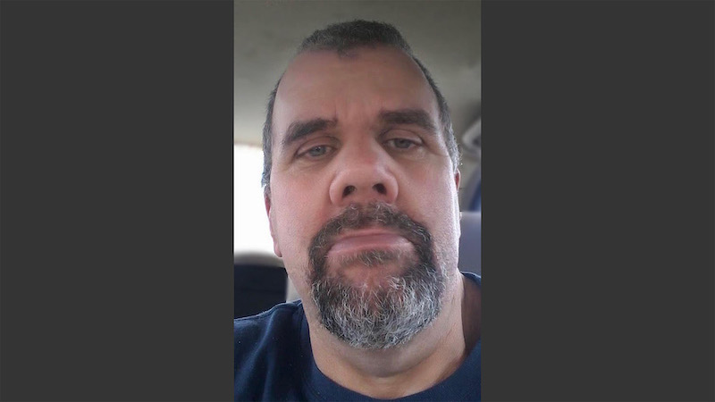 A man with gray hair and beard in the car.
