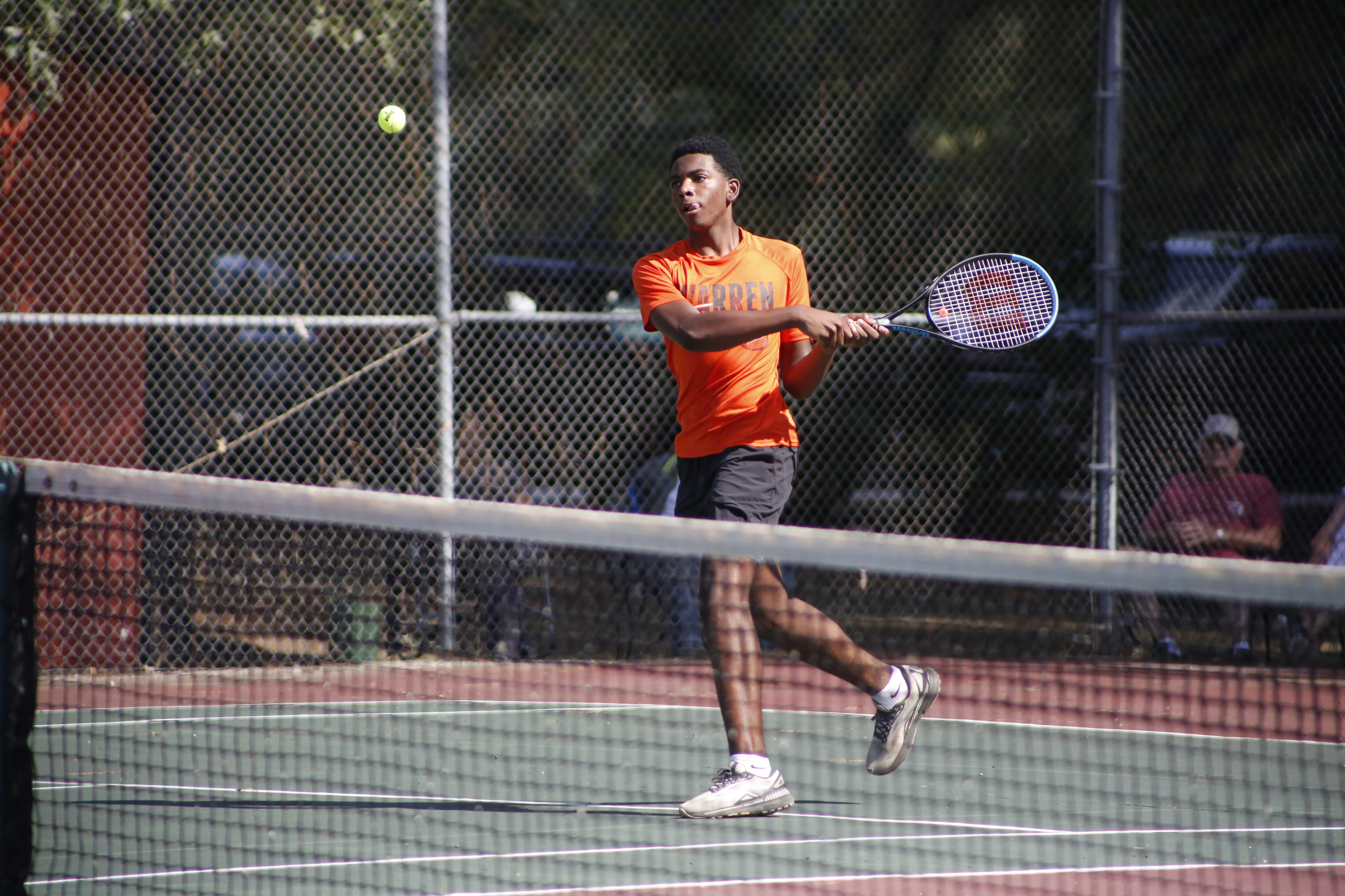 A man swinging at a tennis ball with his racket.