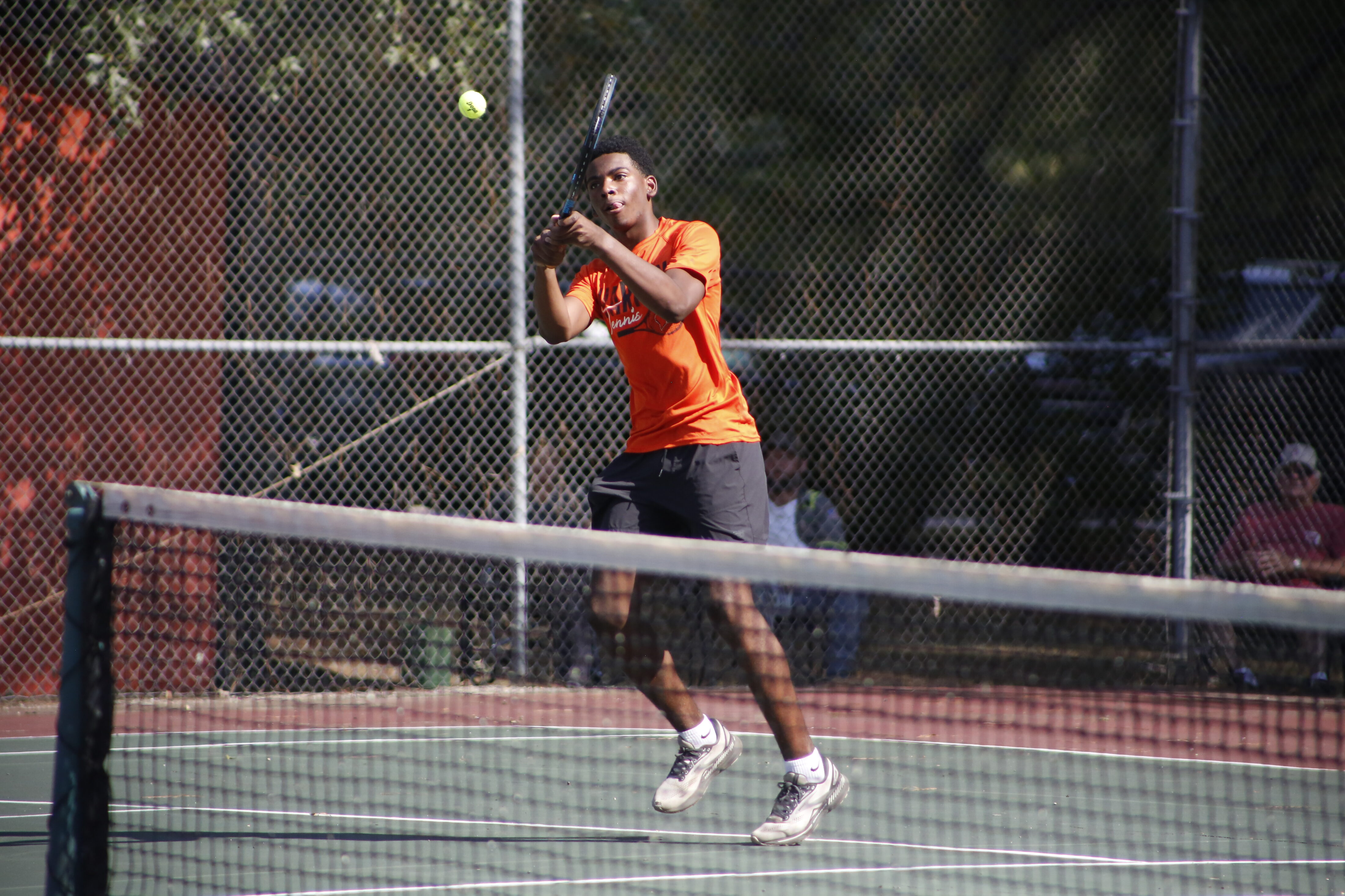 A man swinging at a tennis ball with his racket.