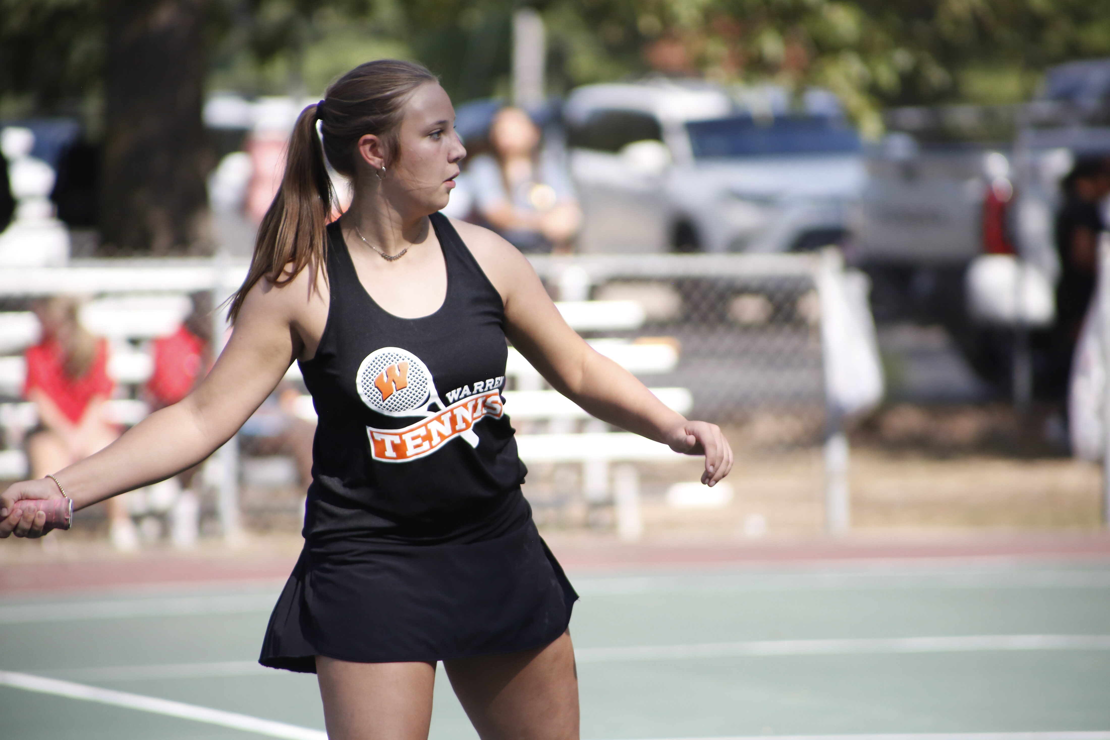 A woman in black shirt playing tennis on court.