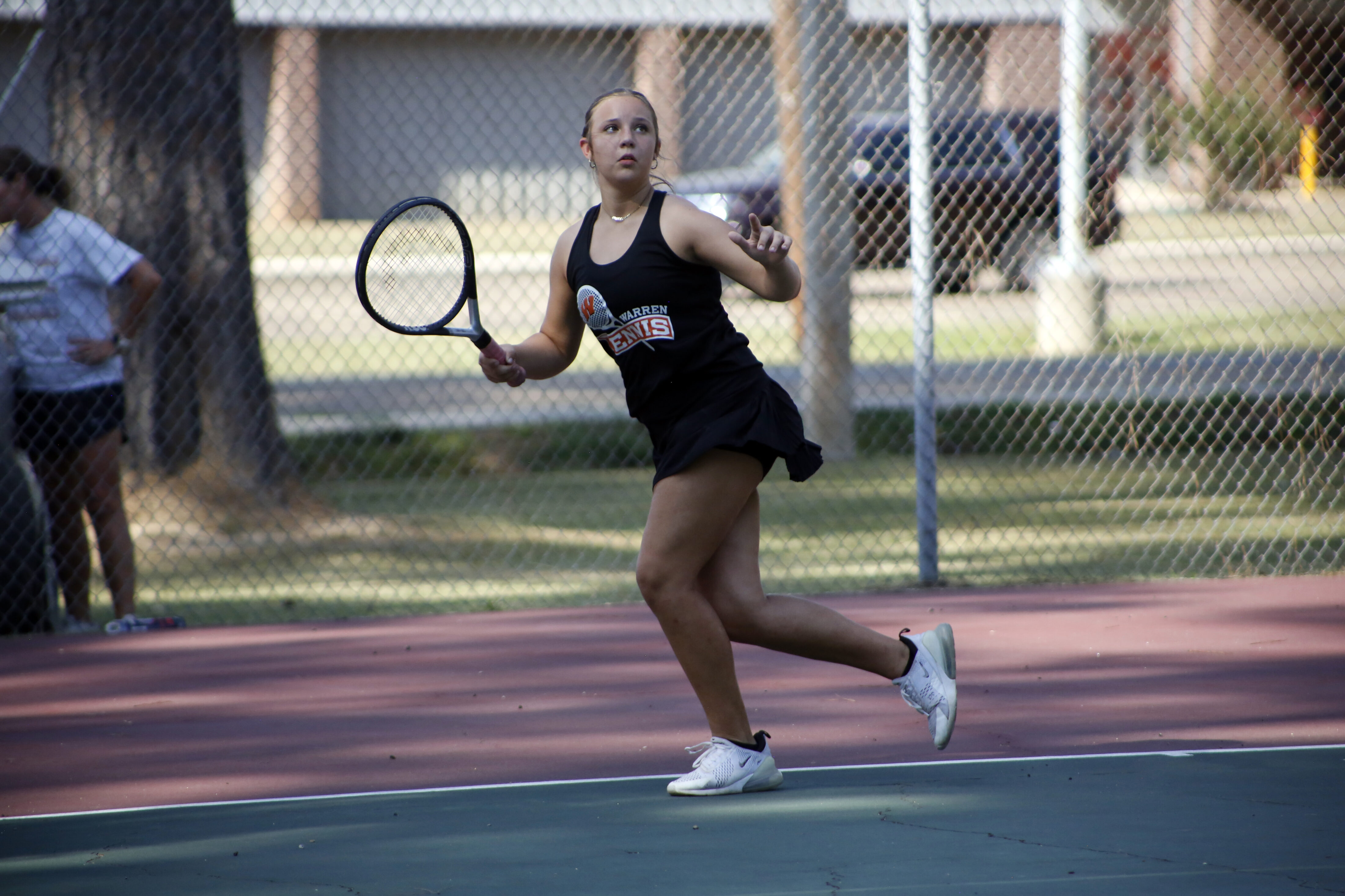A woman swinging at the ball with her tennis racket.