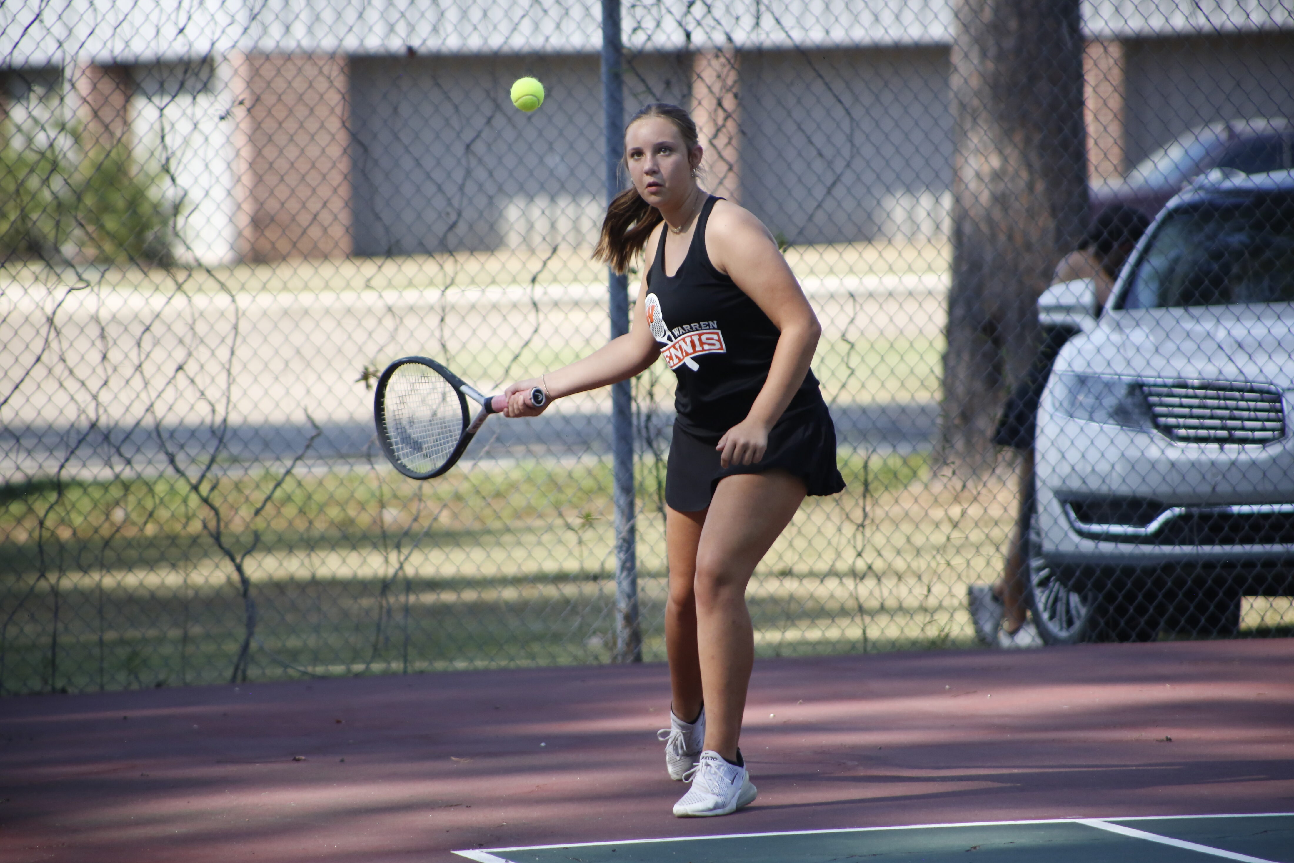 A woman swinging at a tennis ball with her racket.