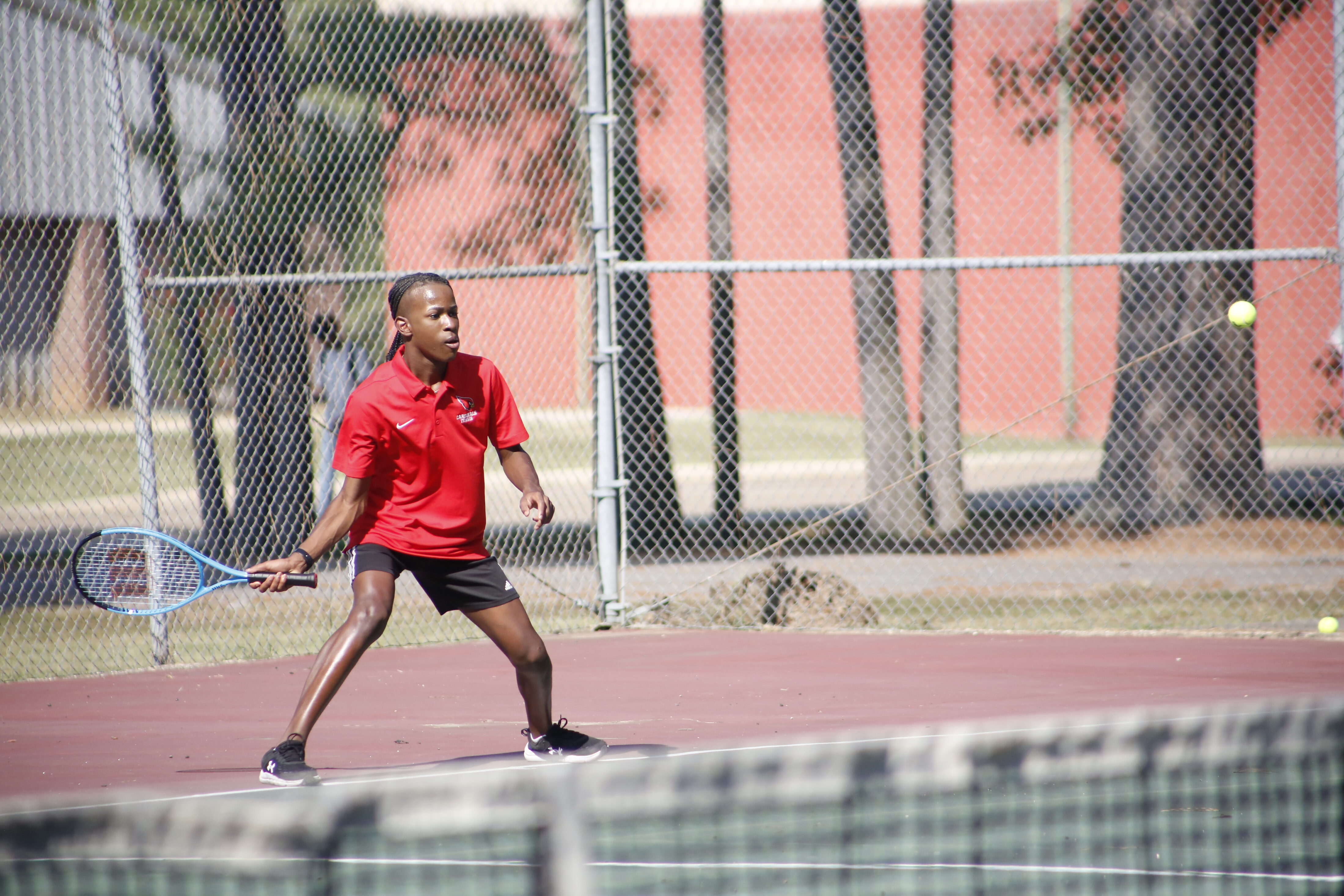 A young man holding a tennis racket on the court